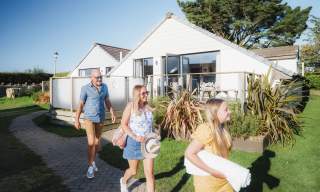 family outside lodge in Holiday Park in summer walking