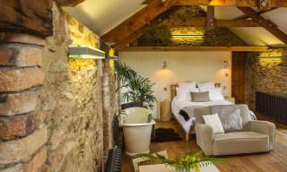 photo of converted barn with a bed and bathtub @ the Yard Devon Yurts