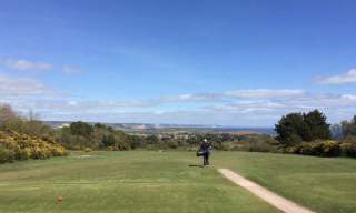golf course and a golfer walking away sea view landscape in a disctance