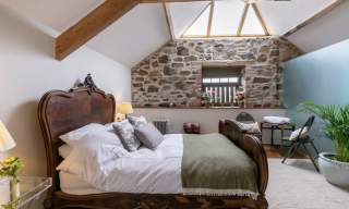king size bed with a skylight over it stone wall in the background
