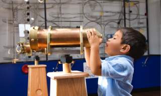Child looking through an old telescope
