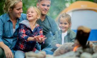 family outside a tent enjoying firepit