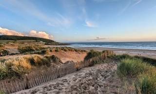 autumnal beach view, sand dunes and clouds in a distance