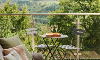 two glasses of champagne sat on a table, with two chairs facing each other on a balcony at The Mole Resort