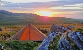 tent pitched at Dartmoor National Park with a view and sunset in a background