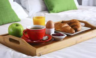 a tray with breakfast on a white bedsheet