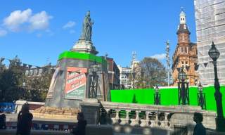 Queen Victoria Square in Hull decorated with wartime Blitz posters. Green screens encircle the square.