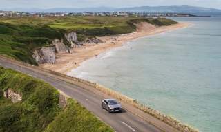 A car driving along the road with Whiterocks Beach in the background