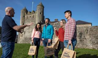 A group in the sunshine outside Enniskillen Castle enjoying an Enniskillen Taste Experience tour.