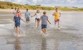 Family enjoying a day out at Ballyhornan Beach, County Down, splashing in the waves.
