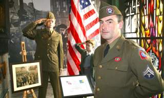 A man dressed up in a uniform from the Second World War standing in the gallery of the Northern Ireland War Memorial Museum