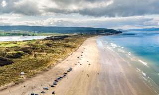 Aerial view of Portstewart beach with cars parked along the stretch of sand.