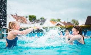 Two girls splashing water on each other