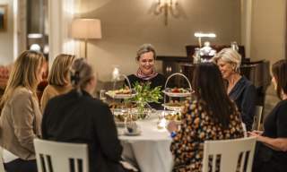 En gruppe damer som sitter rundt et dekket bord på Borregaard Hovedgård og har afternoon tea.