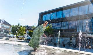 En dame som leker seg i fontenen på Skjønhaug torg