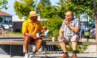 To som tar en kaffekopp på en benk på Skjønhaug torg