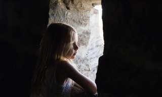 Jente som kikker ut av en åpning i fortet