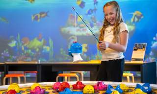 Smilende jente som tester det store fiskespillet på INSPIRIA science center
