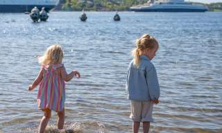 To små jenter i strandkanten på Sjøbadet, med Bastøfergen i bakgrunn