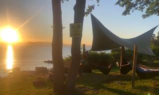 Hengekøye med tarp i solnedgang ved et vann
