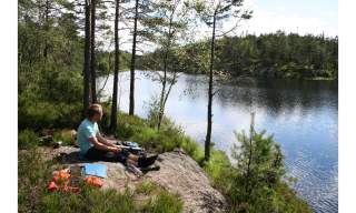 En gutt som sitter ved ett vann og titter utover