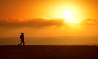 A lone walker on the South Downs in Sussex at sunset