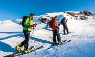 Skikjørere går mot fjelltopp.Foto
