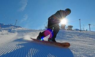 snowboarder i nypløyd bakke med sol og blå himmel i Setesdal