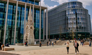 People walking around a renovated fountain in front of modern commercial buildings in Birmingham's Paradise
