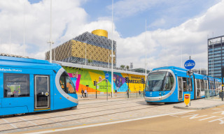 Two blue West Midlands trams outside of Birmingham library