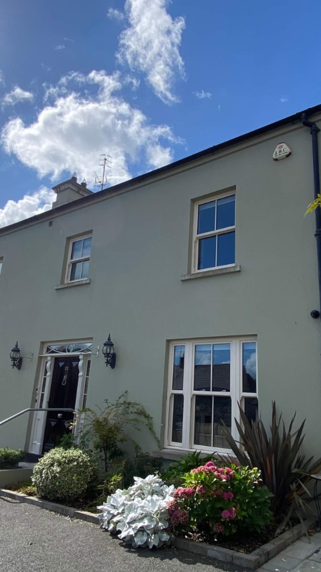 Exterior shot of Bramley House, a self-catering property in County Down.  There are plants outside the front of the house, and the sun is shining with blue skies.