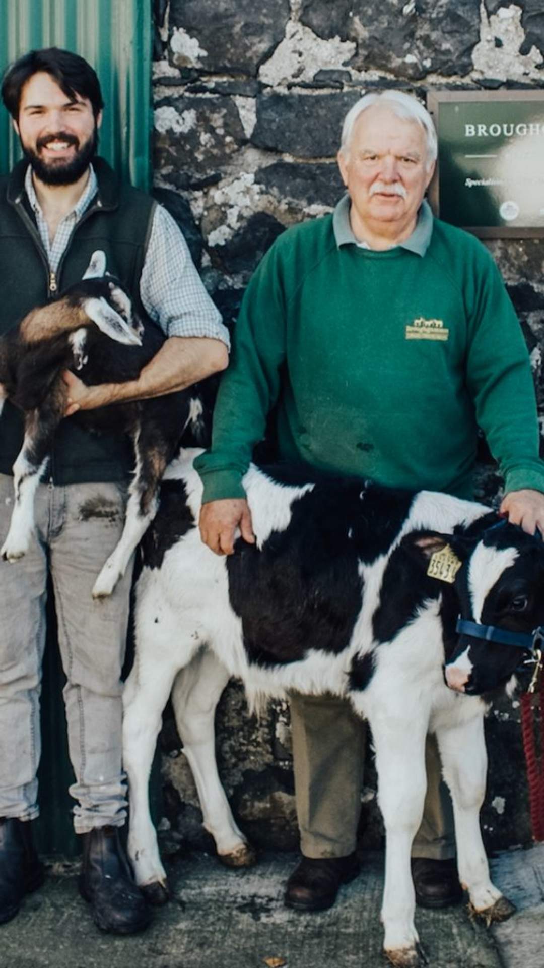 Group of 4 adults and 2 children standing in front of Broughgammon Farm with a calf at the front of the group.