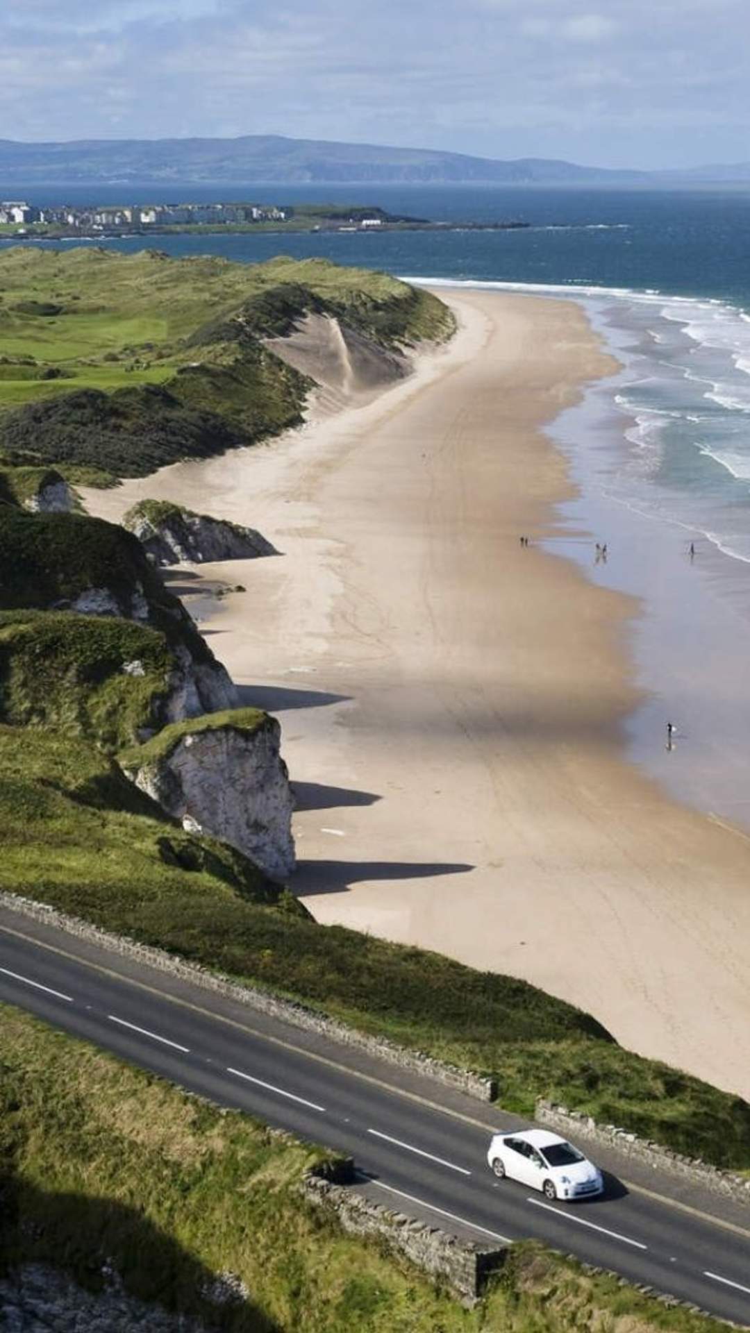Aerial view of a car along the Causeway Coastal Route on a sunny day with the beach in the background