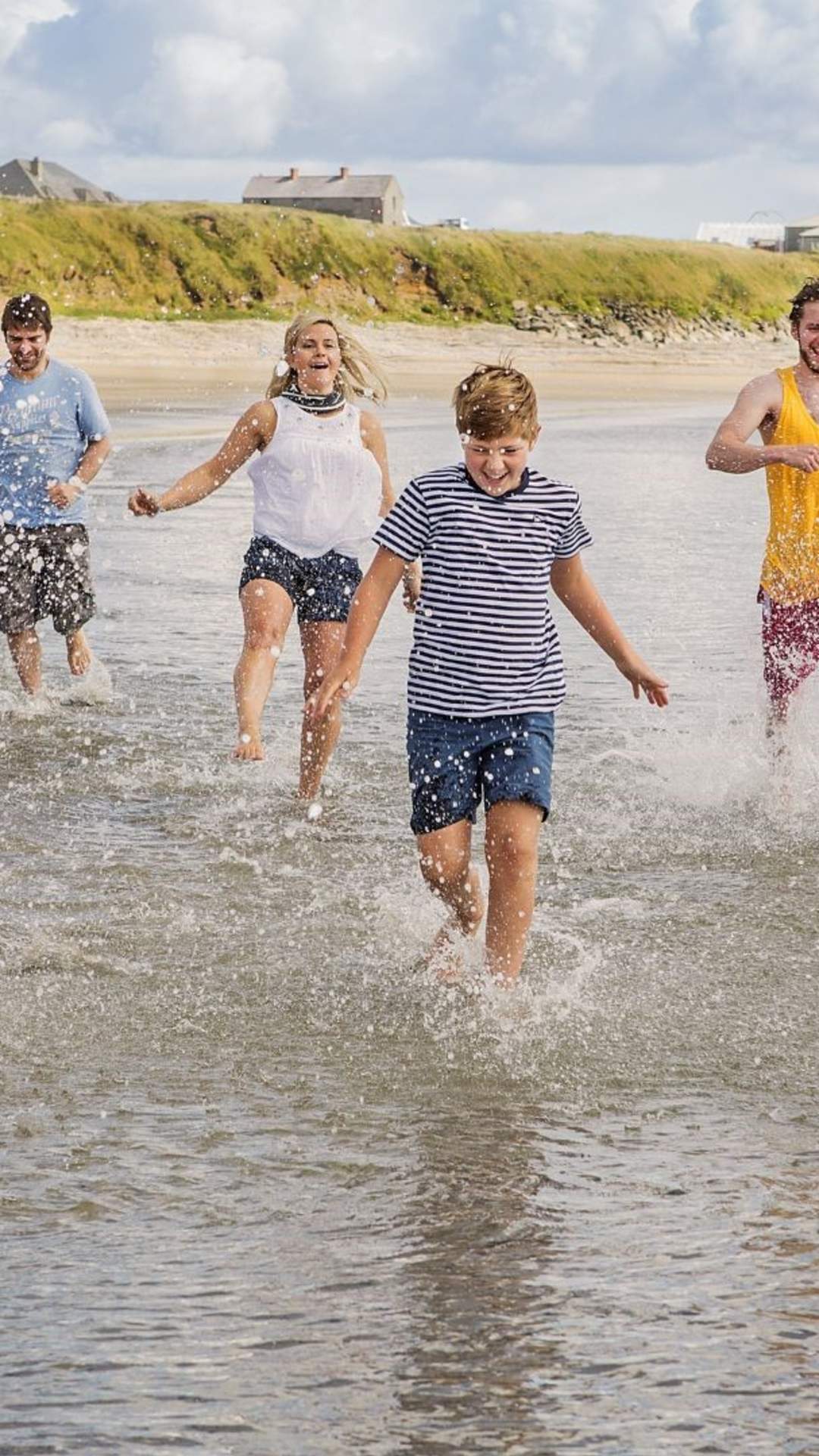 Family enjoying a day out at Ballyhornan Beach, County Down, splashing in the waves
