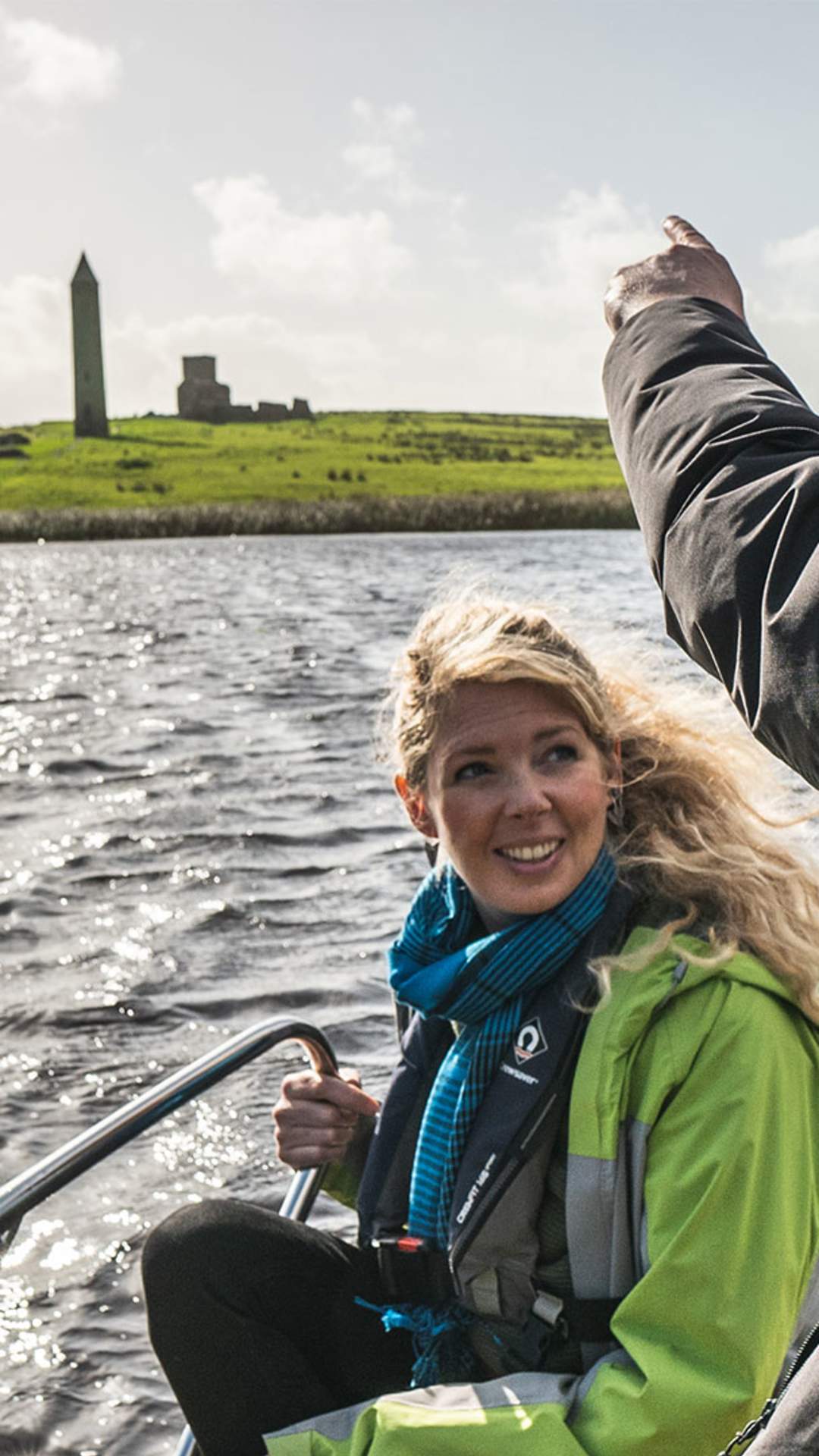 A passenger points to Devenish Island while onboard a water taxi which can be viewed from the shores of Lough Erne on the boat tour