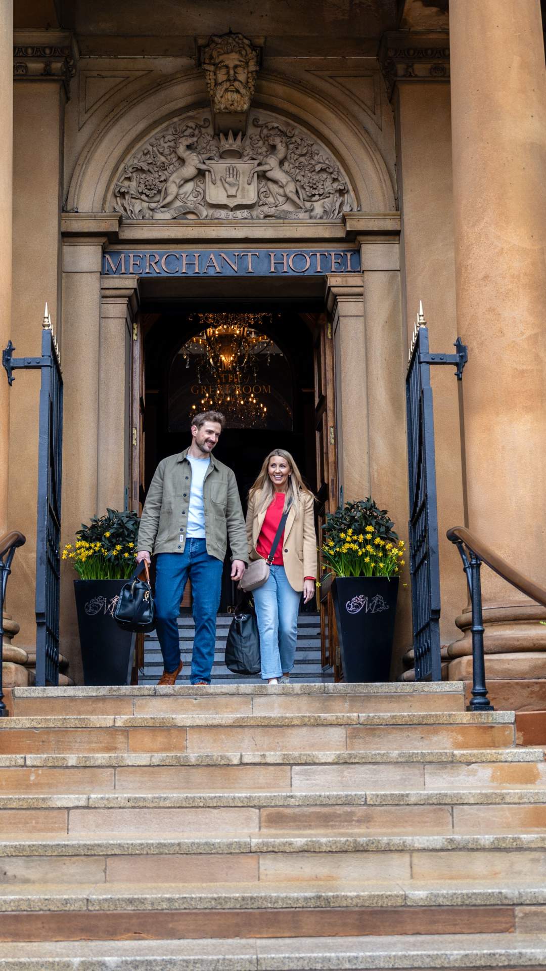 A couple walking down the steps outside The Merchant Hotel in Belfast.