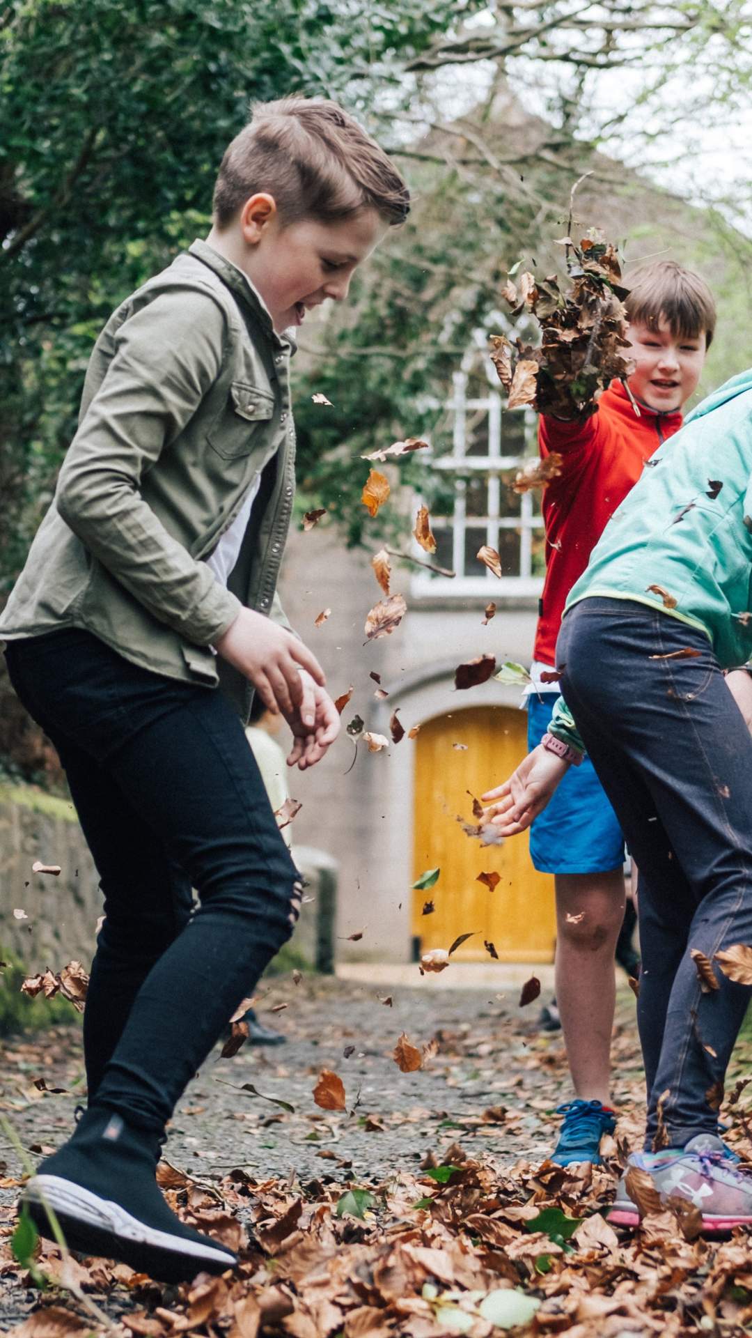 Children playing in the Autumn leaves at the Ulster Folk Museum.