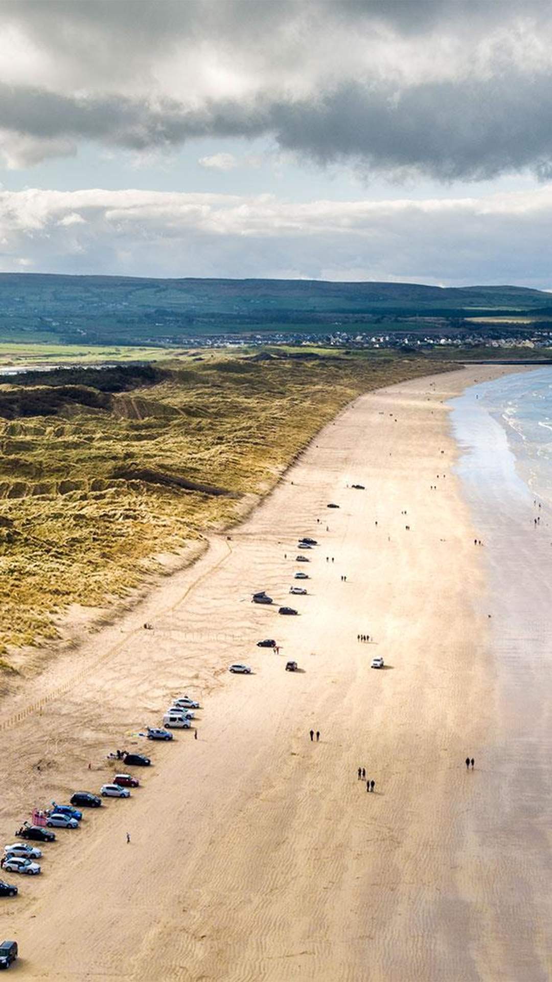 Aerial view of Portstewart beach with cars parked along the stretch of sand.