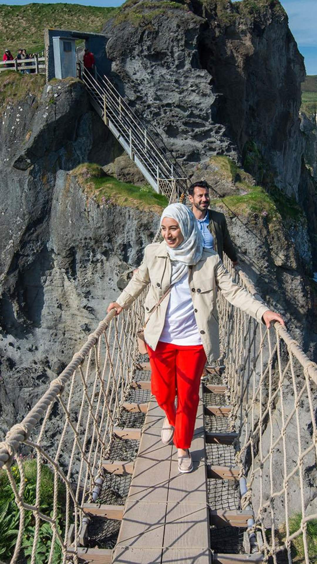 Stunning views of Carrick-a-Rede Rope Bridge, along the Causeway Coastal Route as a couple cross the bridge.