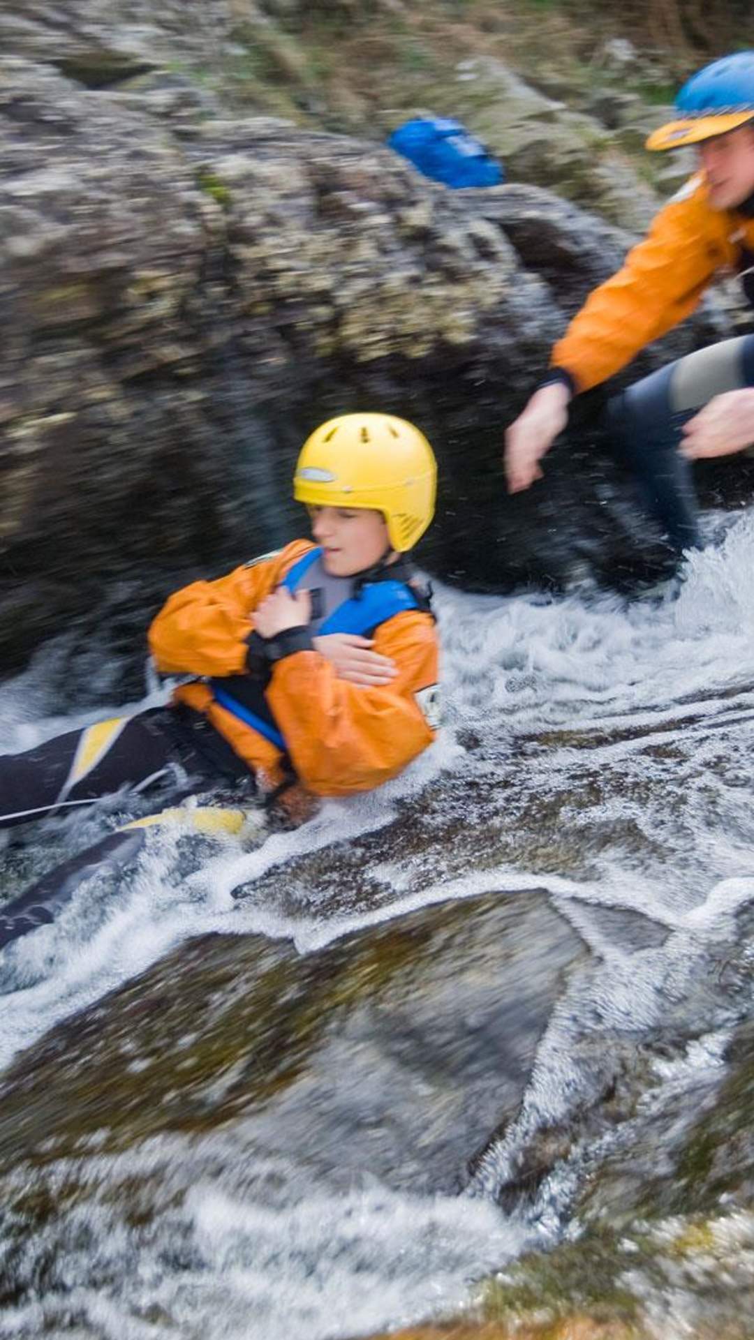 Bouldering at Bloody Bridge in Newcastle, County Down. Man slides down whitewater rocks.