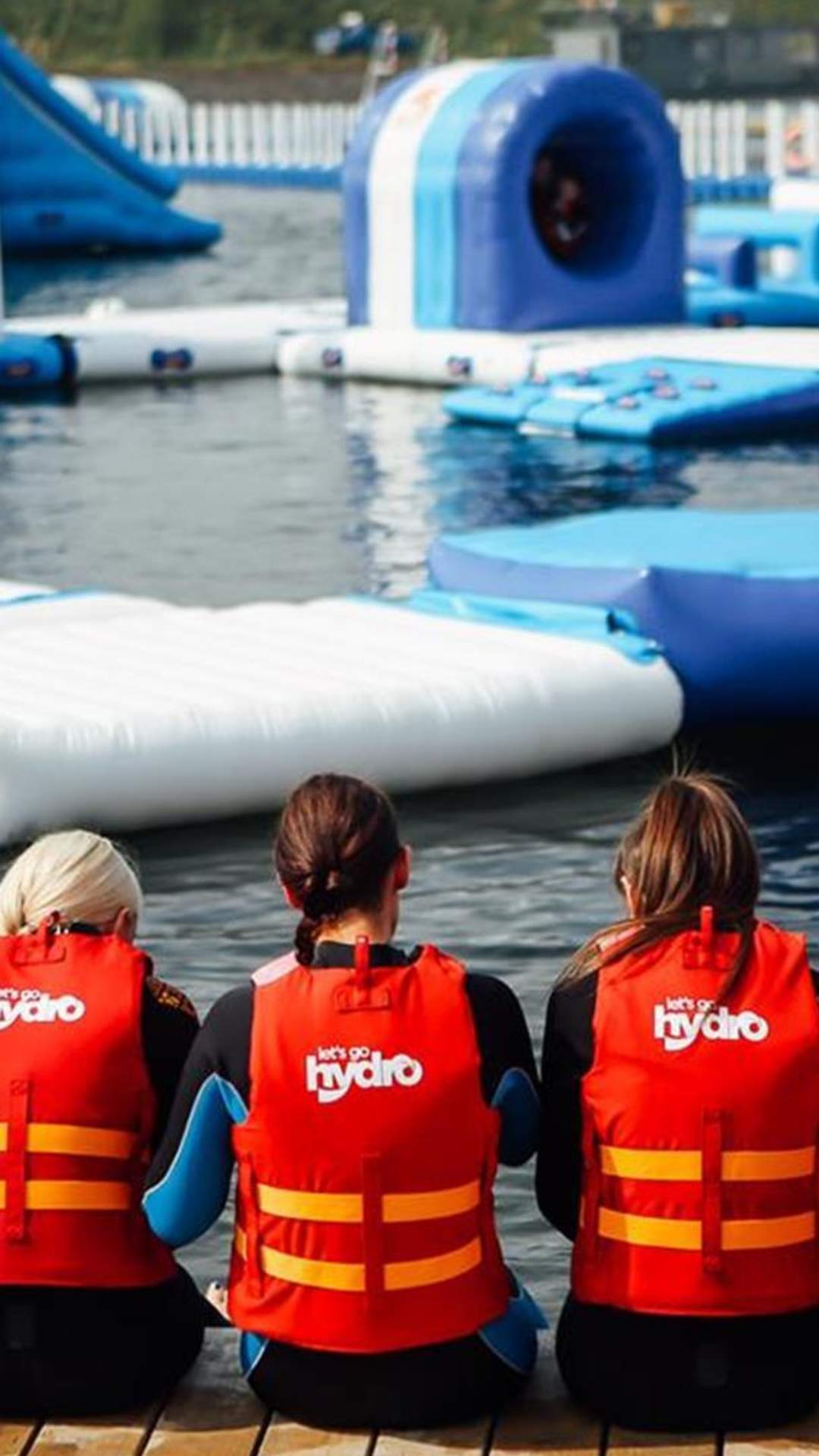 Image shows children wearing life jackets, sitting on the edge of the lake