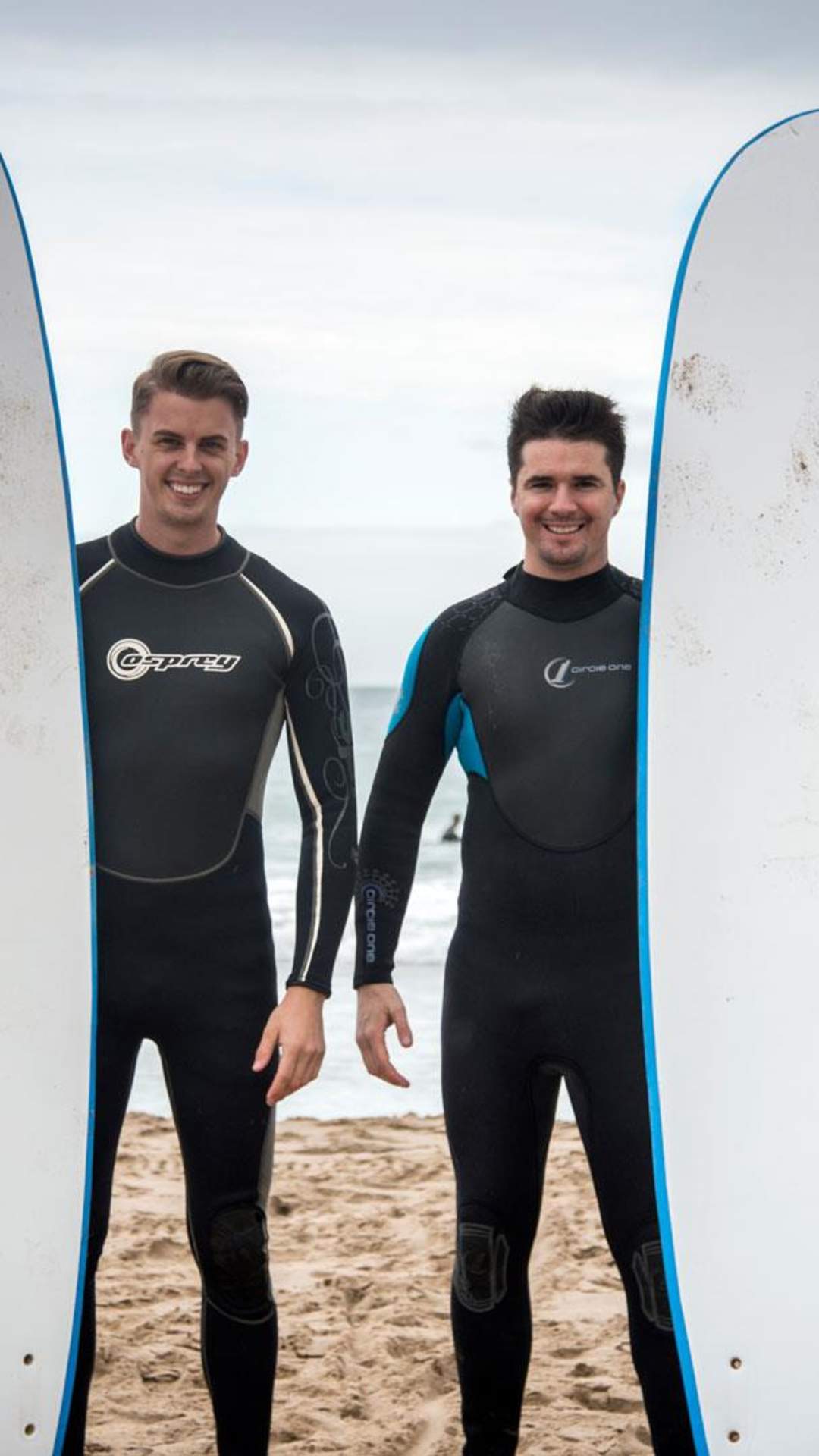 Two surfers pose with their boards in front of the sea Whiterocks Beach, Portrush, County Antri