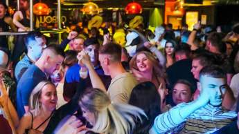 Club goers dancing under a disco ball on the dancefloor at Popworld