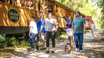 People enjoying a beautiful day walking alongside the steam engine on the heritage rail trail