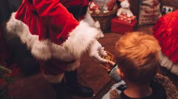 A Santa hand handing a small gift to a child - Credit Avon Valley Adventure and Wildlife Park