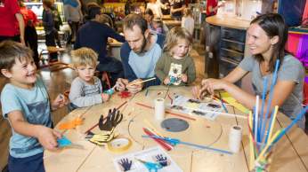 Family trying the bionic hands activity at We The Curious Bristol - credit Paul Blakemore