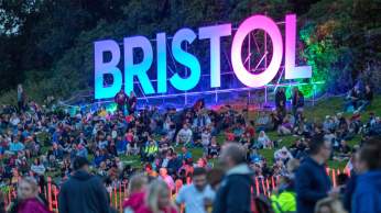 People sitting around a luminous Bristol sign at Bristol International Balloon Fiesta - credit Paul Box