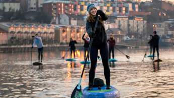 A group of people stand-up paddleboarding in Bristol Harbour - credit Paul Box