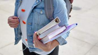 A female university student carrying a handful of books