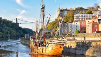 A view of The Matthew replica ship passing through Bristol's Cumberland Basin with the Clifton Suspension Bridge in the background - credit Nick Greville